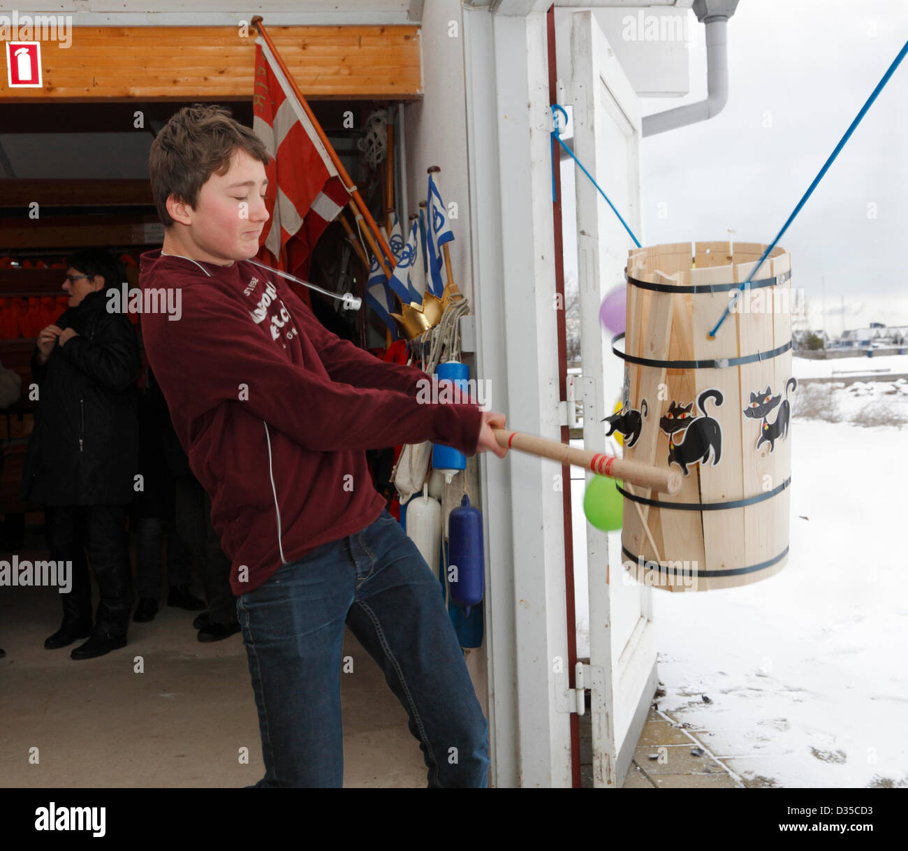 Febbraio, domenica 10, 2013 - Rungsted Rowing Club, Danimarca. Ragazzo adolescente, troppo vecchio per il fancy dress, prendendo parte al vecchio Shrovetide danese personalizzato per battere il gatto della canna. Esso combina antiche credenze cristiane e pagane rituali - originariamente fatto collocando un live cat in un barile. Oggi con i gatti di cartone e un opportunità per i bambini e gli adulti a vestire e celebrare il passaggio dall'inverno alla primavera e competere per diventare il Shrovetide Queen o King (fondo o ultima canna doga). Poi focacce, cacao, e caramelle. La tradizione è effettuata nella comunità, scuole, club, ecc. Foto Stock