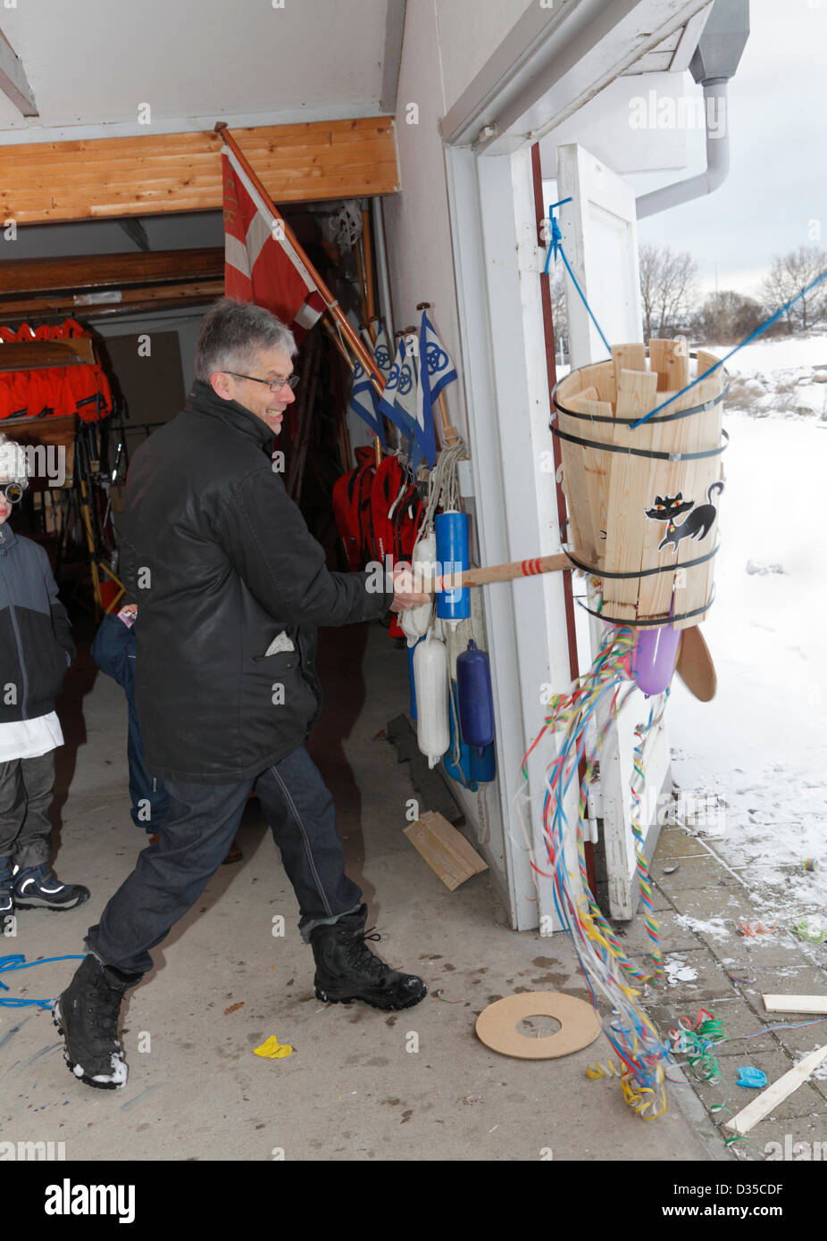 Febbraio, domenica 10, 2013 - Rungsted Rowing Club, Danimarca. Vogatore maschio prendendo parte al vecchio Shrovetide danese personalizzato per battere il gatto della canna. Esso combina antiche credenze cristiane e pagane rituali - originariamente fatto collocando un live cat in un barile. Oggi con i gatti di cartone e un opportunità per i bambini e gli adulti a vestire e celebrare il passaggio dall'inverno alla primavera e competere per diventare il Shrovetide letti Queen o King (nella parte inferiore del cilindro o canna ultima doga). Poi focacce, cacao, e caramelle. La tradizione è effettuata nella comunità, scuole, circoli sportivi, ecc. Foto Stock