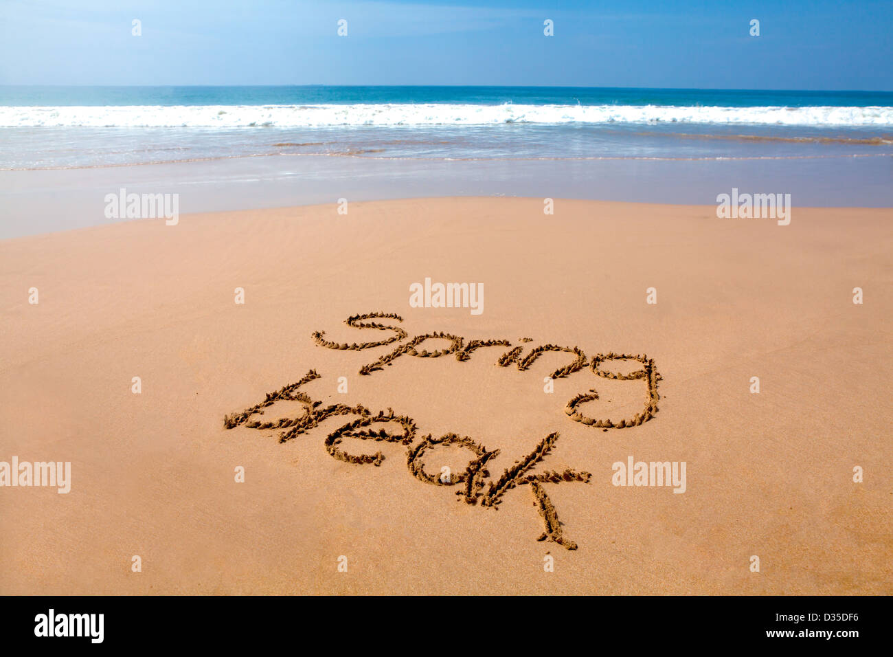 Parole spring break scritto in sabbia su una spiaggia tropicale, con il mare in background Foto Stock