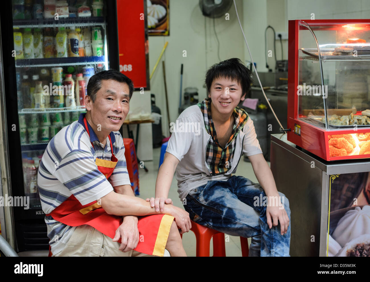 Azienda di famiglia: allegro negozianti seduti nei loro cinese gnocco shop Foto Stock