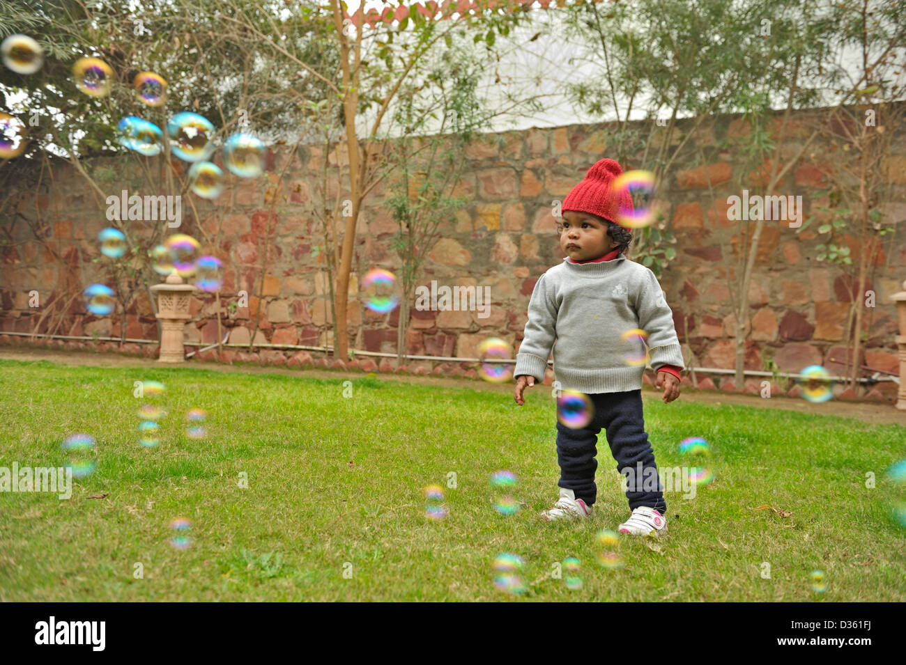 Indian bambina gioca con le bolle in un giardino Foto Stock