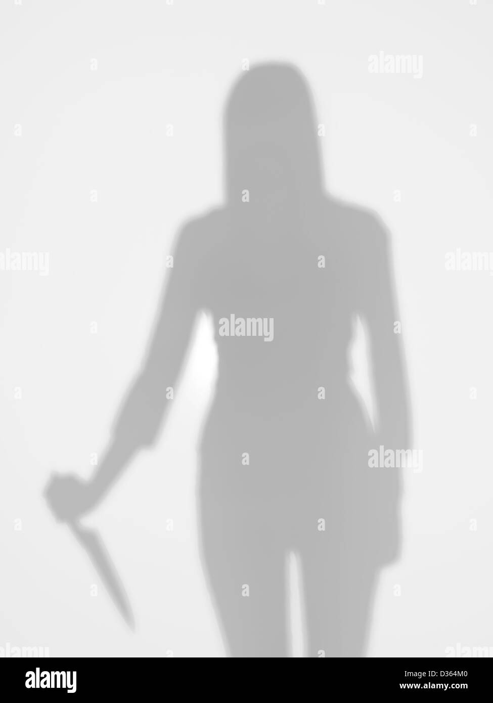 Silhouette femmina tenendo un coltello nella sua mano dietro una superficie diffusa Foto Stock