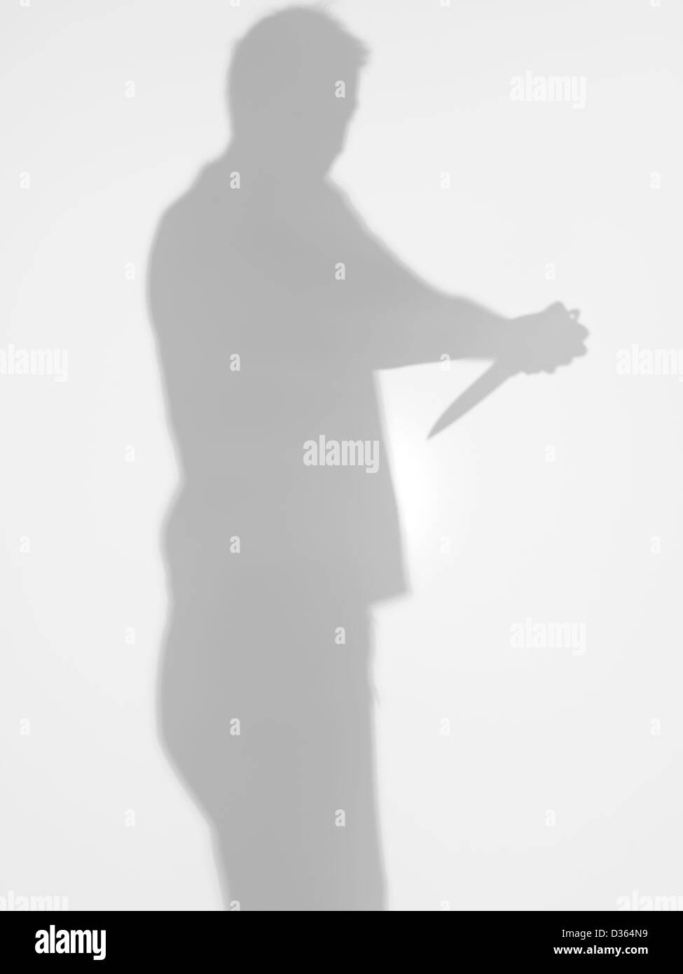 Silhouette uomo in possesso di un coltello nelle sue mani puntando verso di sé il tentativo di suicidio, in piedi dal profilo, dietro un Foto Stock
