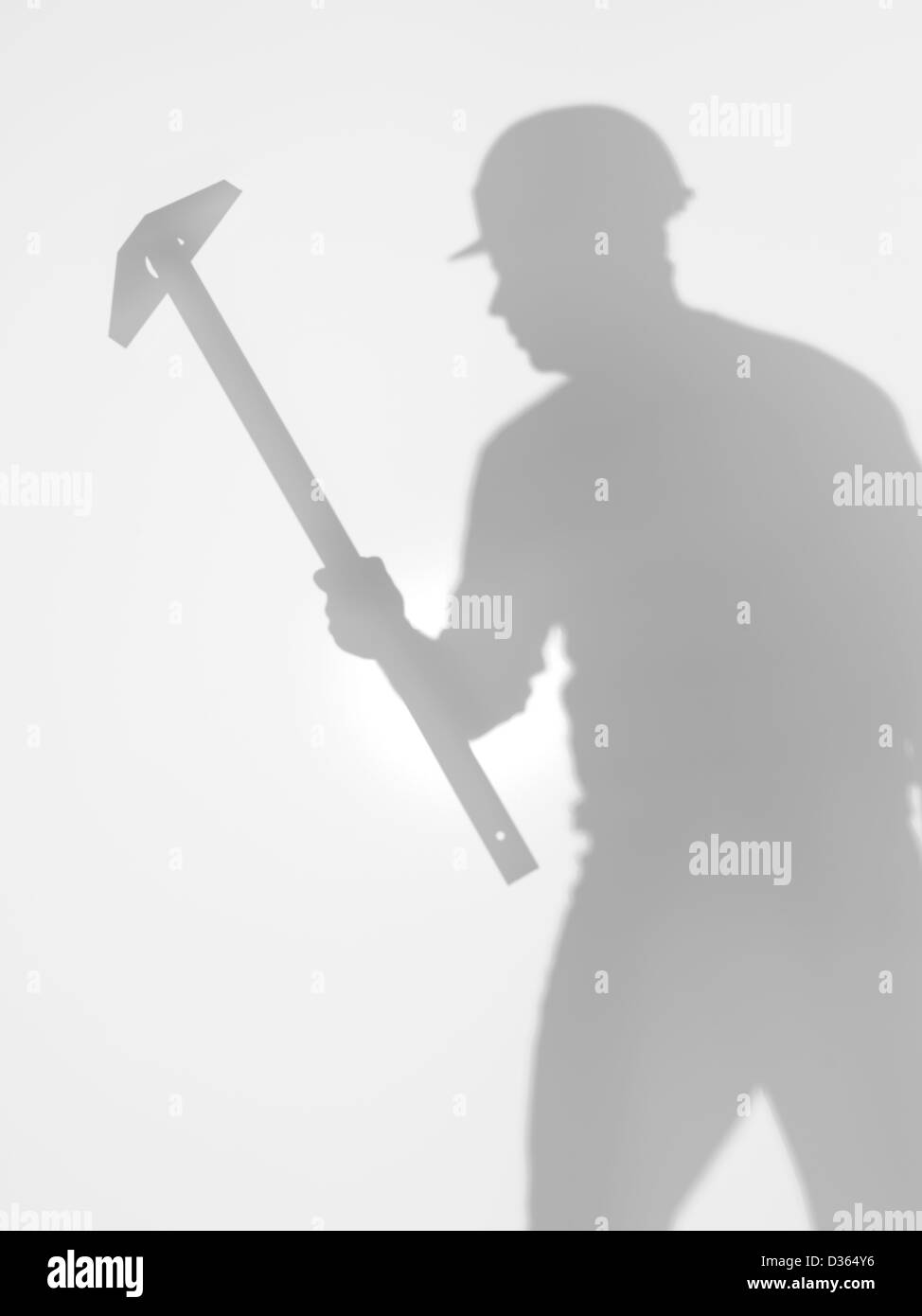 Un uomo lavoratore edile con hardhat e un t square dominatore nelle sue mani e piedi, silhouette, dietro una superficie diffusa Foto Stock