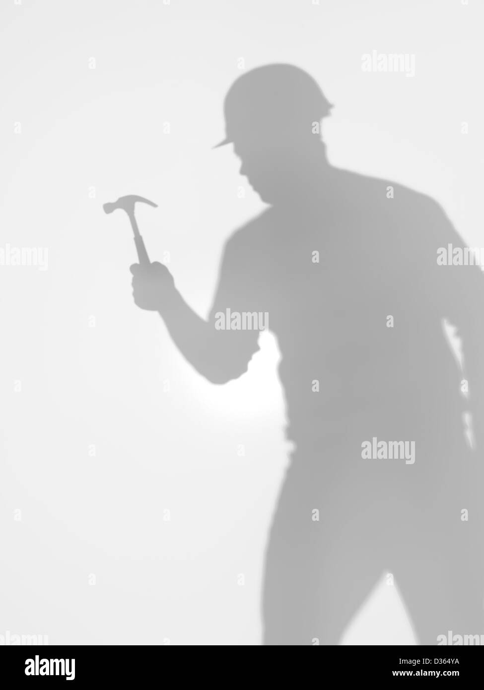 Silhouette di un lavoratore edile con hardhat e un martello nella sua mano, dietro una superficie diffusa Foto Stock