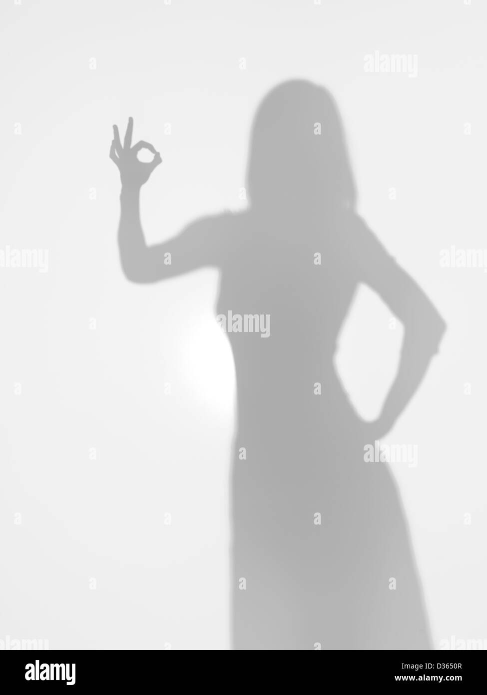 Corpo femmina silhouette facendo un gesto ok con la mano dietro una superficie diffusa Foto Stock