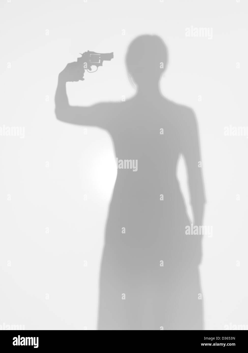 Giovane corpo femmina silhouette in piedi e puntando una pistola verso la sua testa, dietro una superficie diffusa Foto Stock