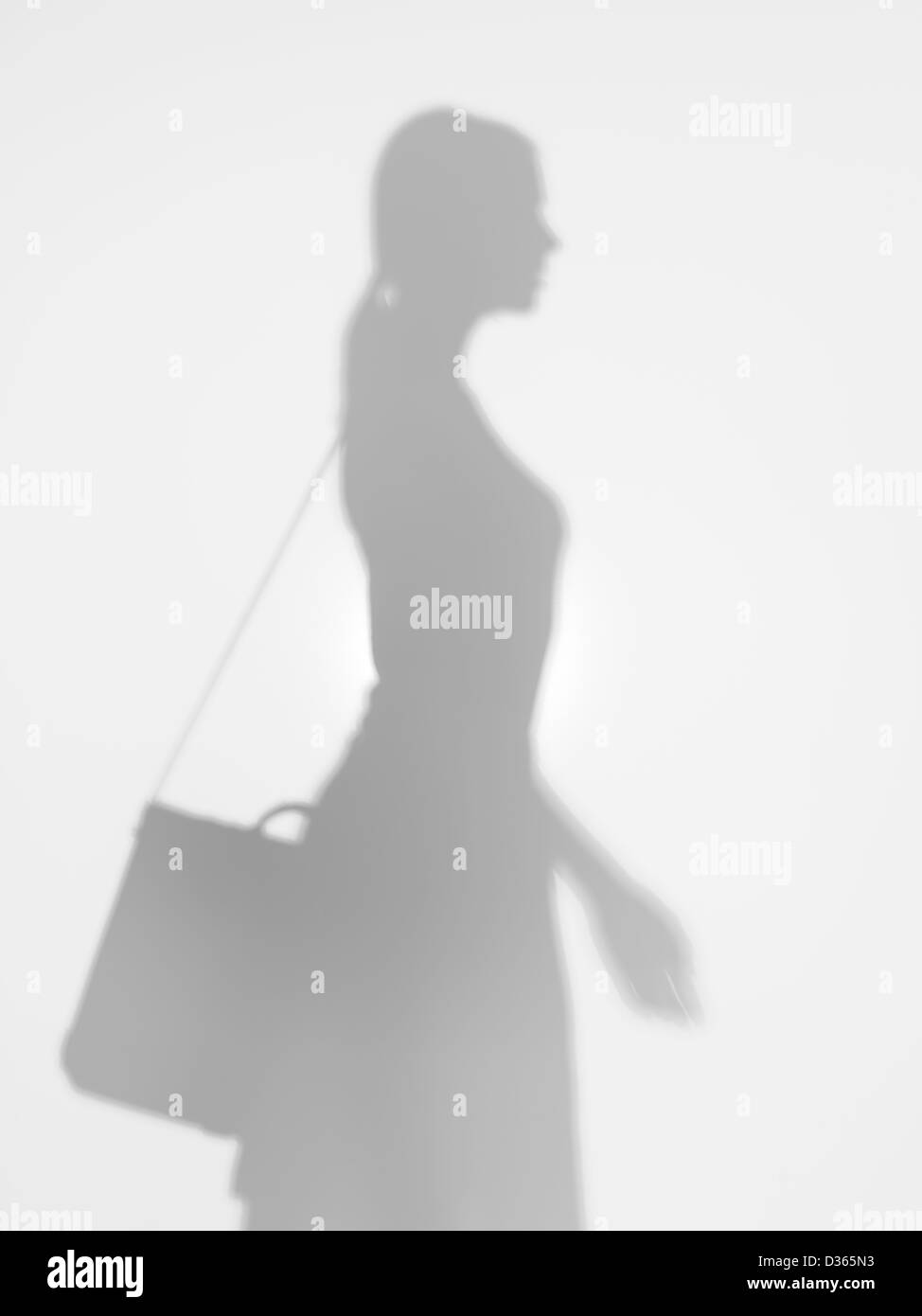 Vista laterale della giovane donna di affari con la borsa a tracolla, camminando dietro una superficie diffusa Foto Stock