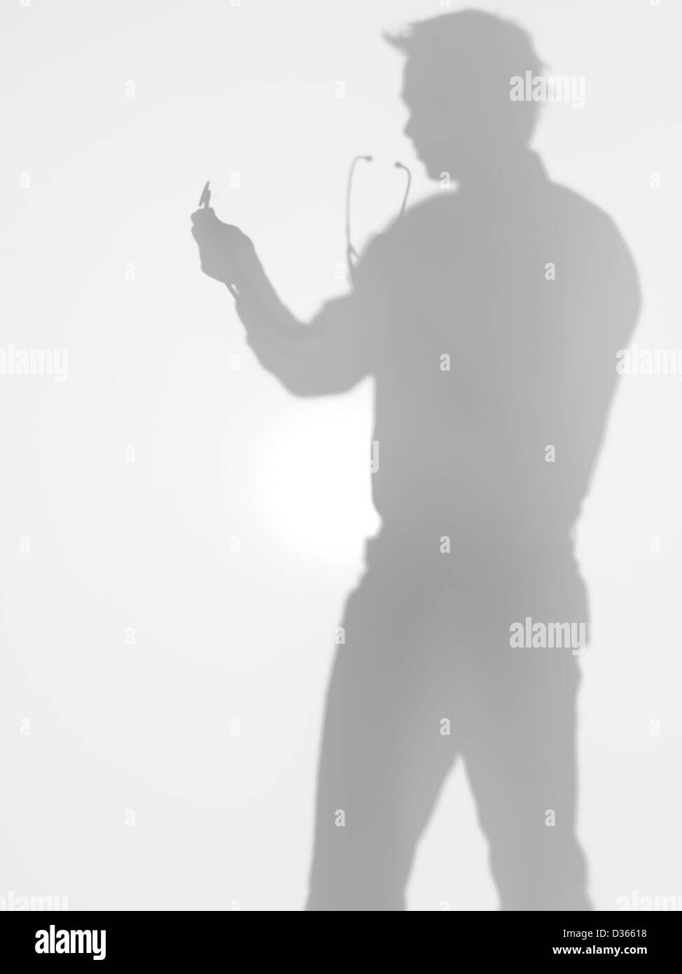 Vista laterale di uomo con uno stetoscopio nelle sue mani davanti a lui e dietro una superficie diffusa Foto Stock