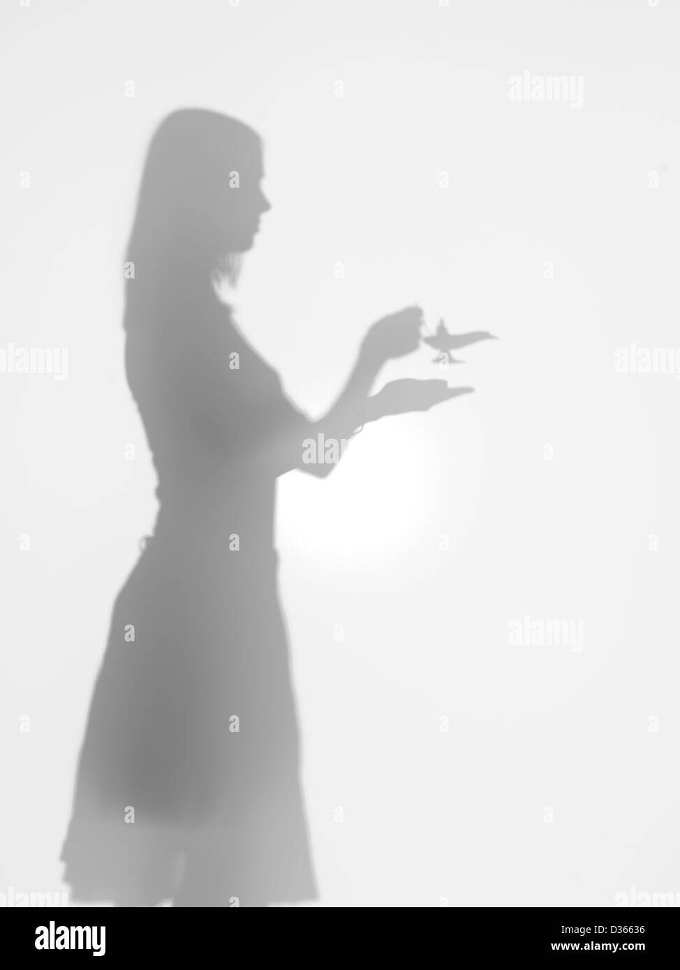 Vista laterale della donna tenendo la lampada di alladin nelle sue mani, dietro una superficie diffusa Foto Stock