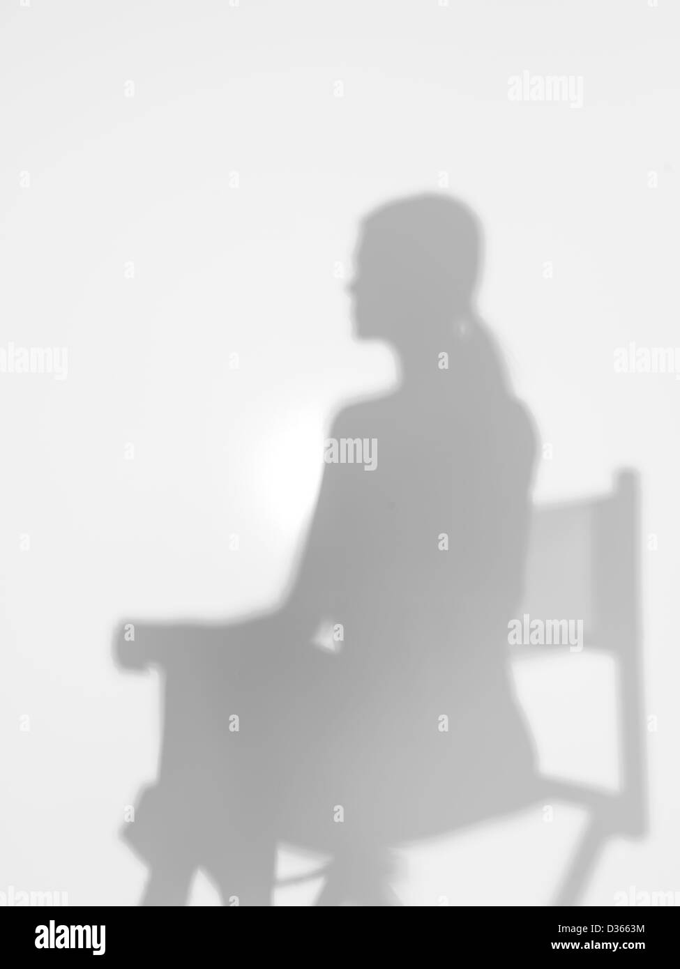 Donna seduta su un direttore di sedia, dietro una superficie diffusa, back lit Foto Stock