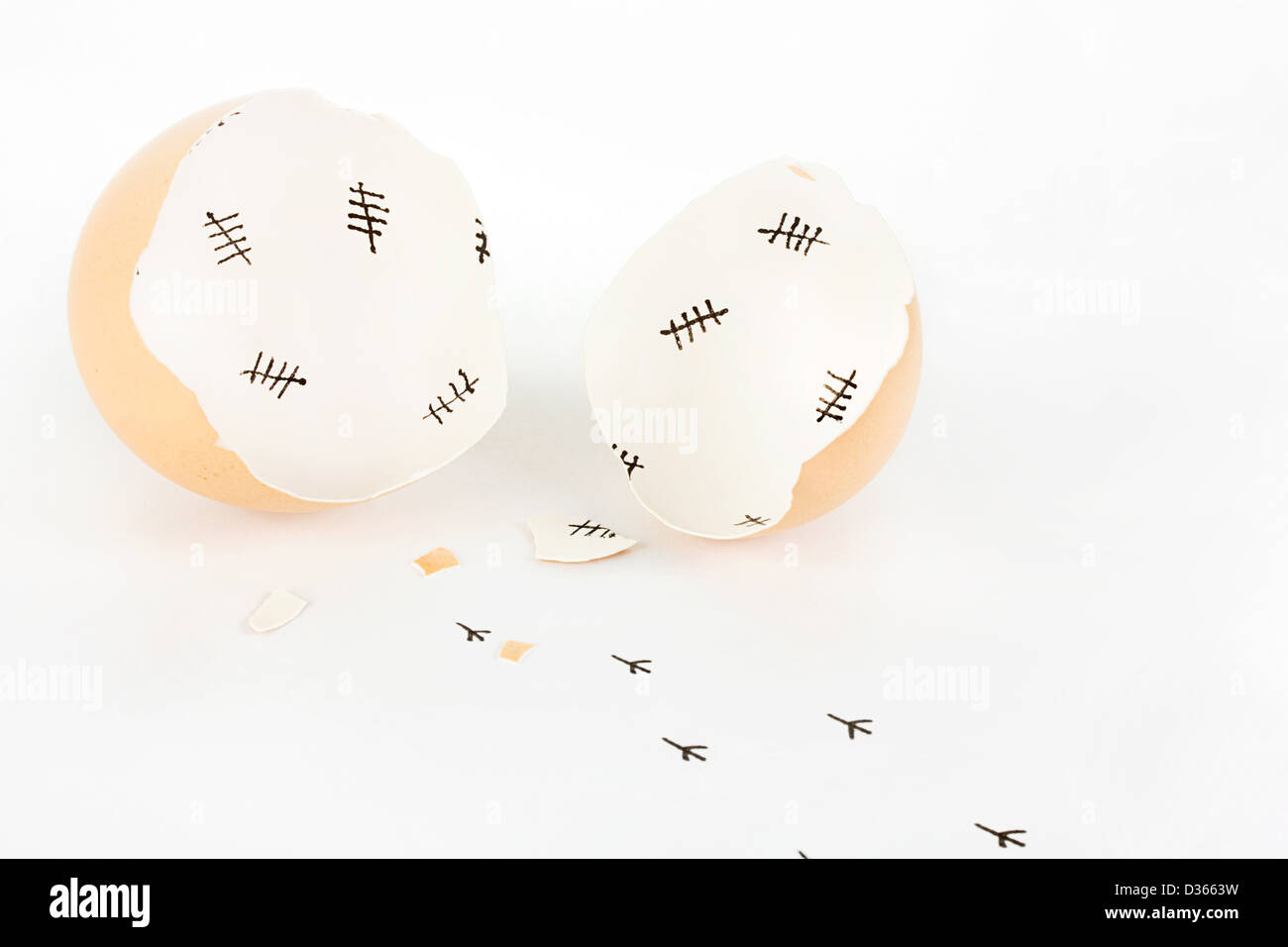 Rotto il guscio delle uova con marchi tally interno e impronte di pulcino su bianco Foto Stock