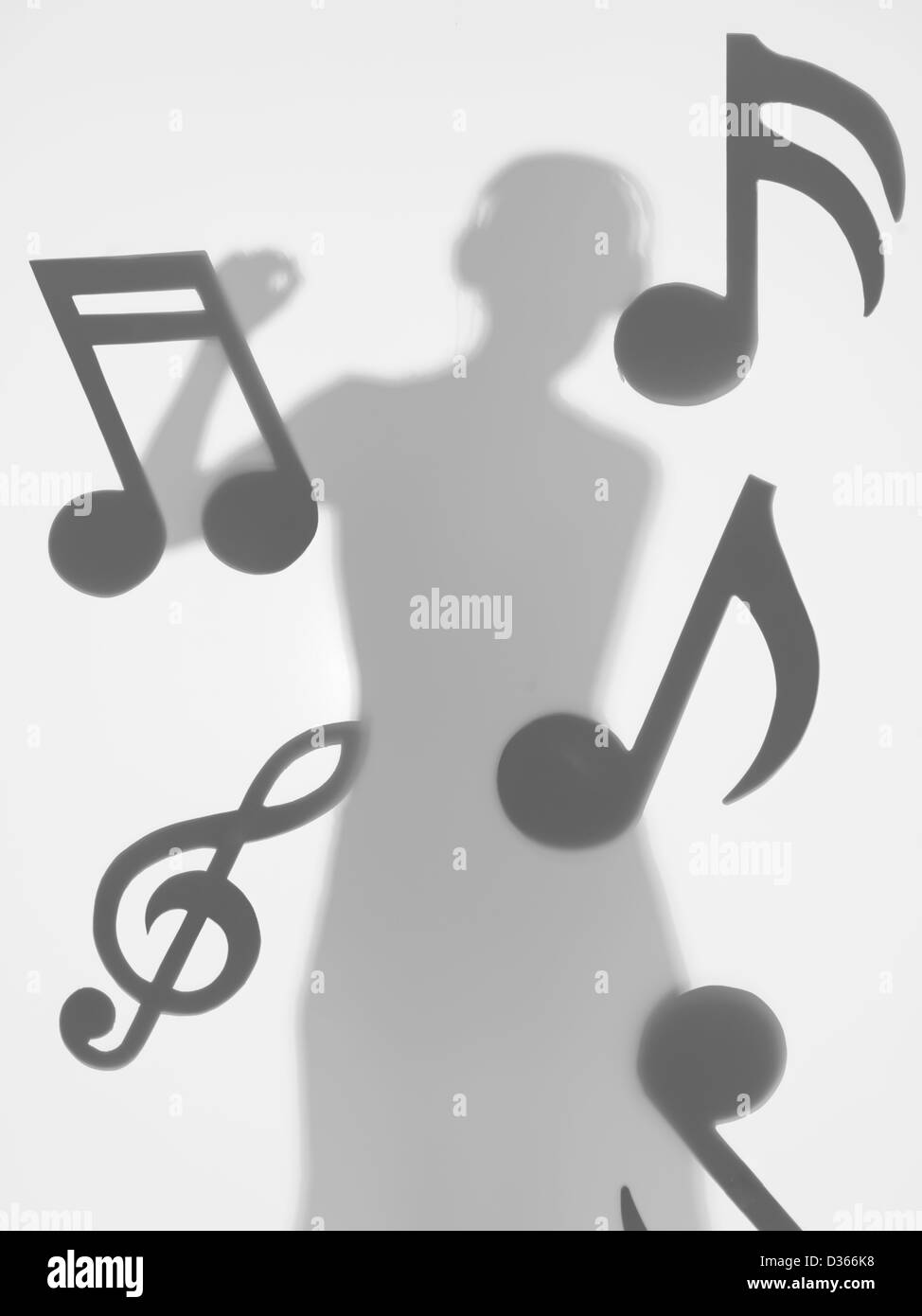 Woman Dancing e ascolto di musica con cuffie, circondato da note musicali, dietro una superficie diffusa Foto Stock