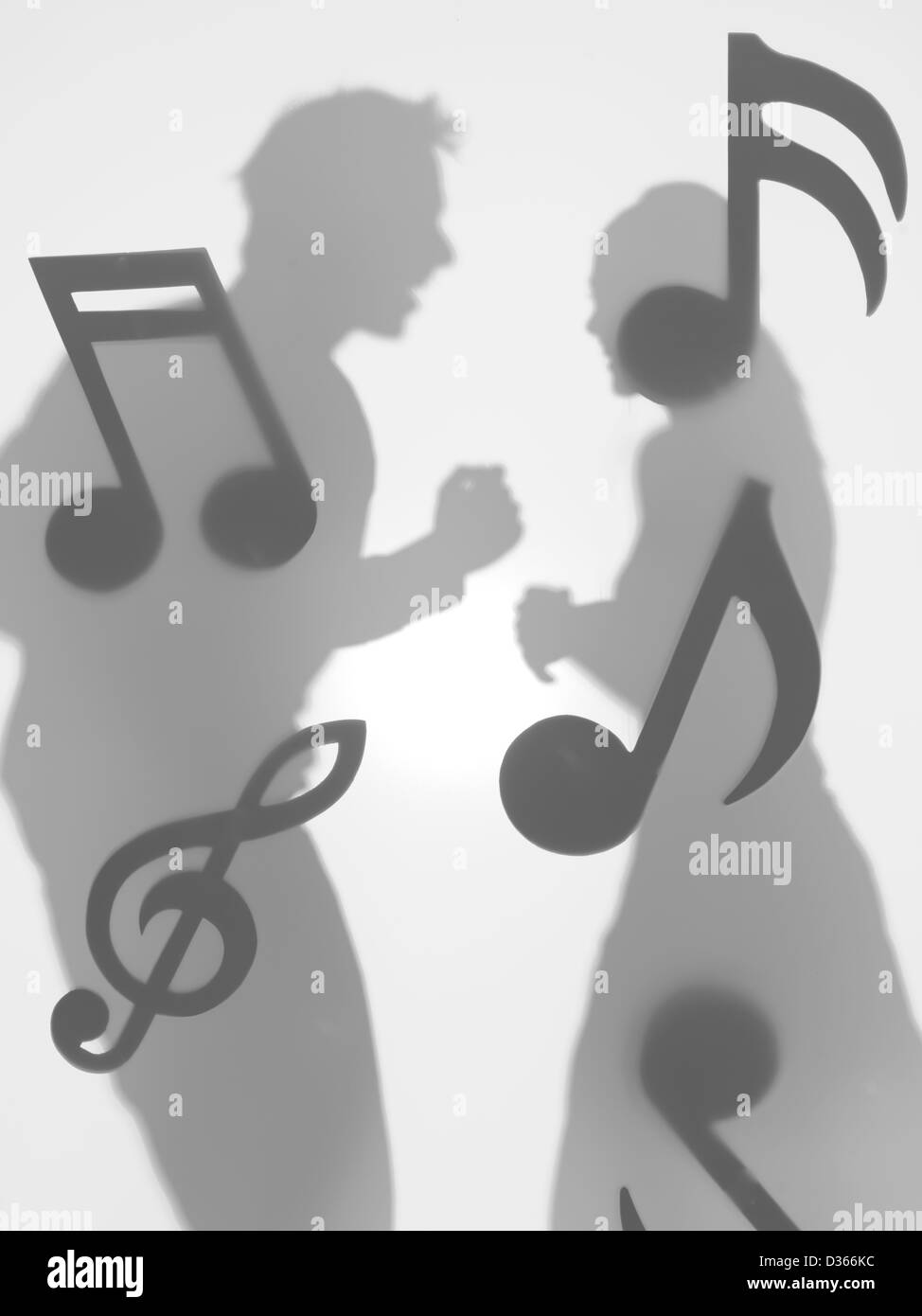 Vista laterale di un uomo e di una donna dancing faccia a faccia, circondato con note musicali, dietro una superficie diffusa Foto Stock