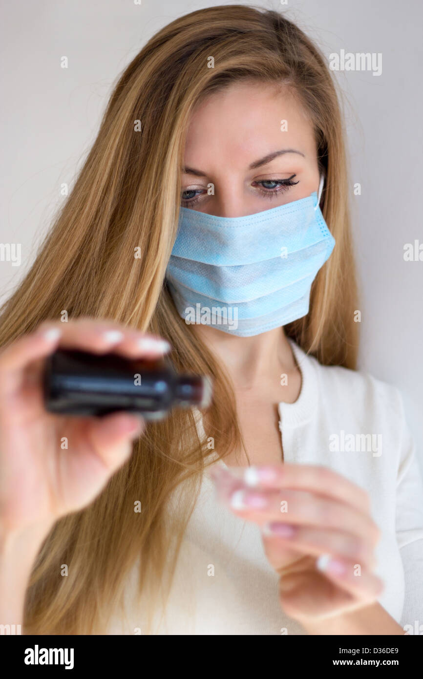 Donna in maschera mano azienda medicina health care sciroppo. Profondità di campo. Foto Stock