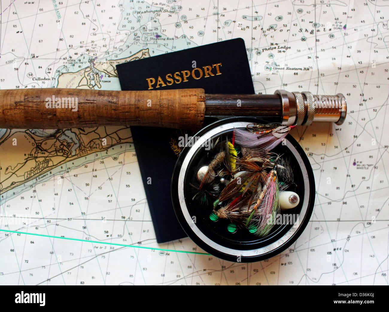Un flyrod reel e poggia su una carta nautica con un passaporto in corso di validità e di mosche artificiali. Foto Stock