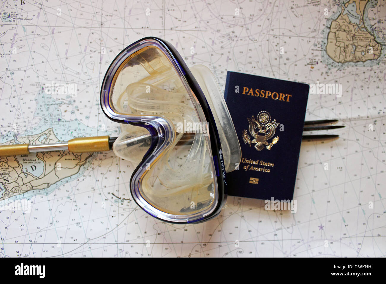 Un polo di pesca subacquea e maschera subacquea con passaporto giacciono su una carta nautica. Foto Stock