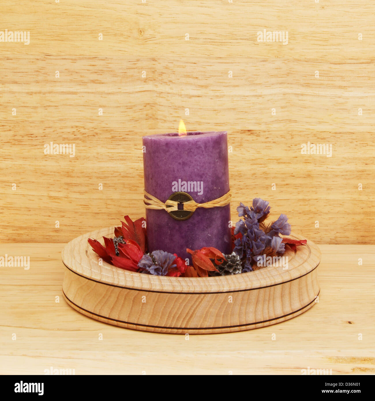 La masterizzazione di viola il Feng Shui candela con pot-pourri in una ciotola di legno Foto Stock