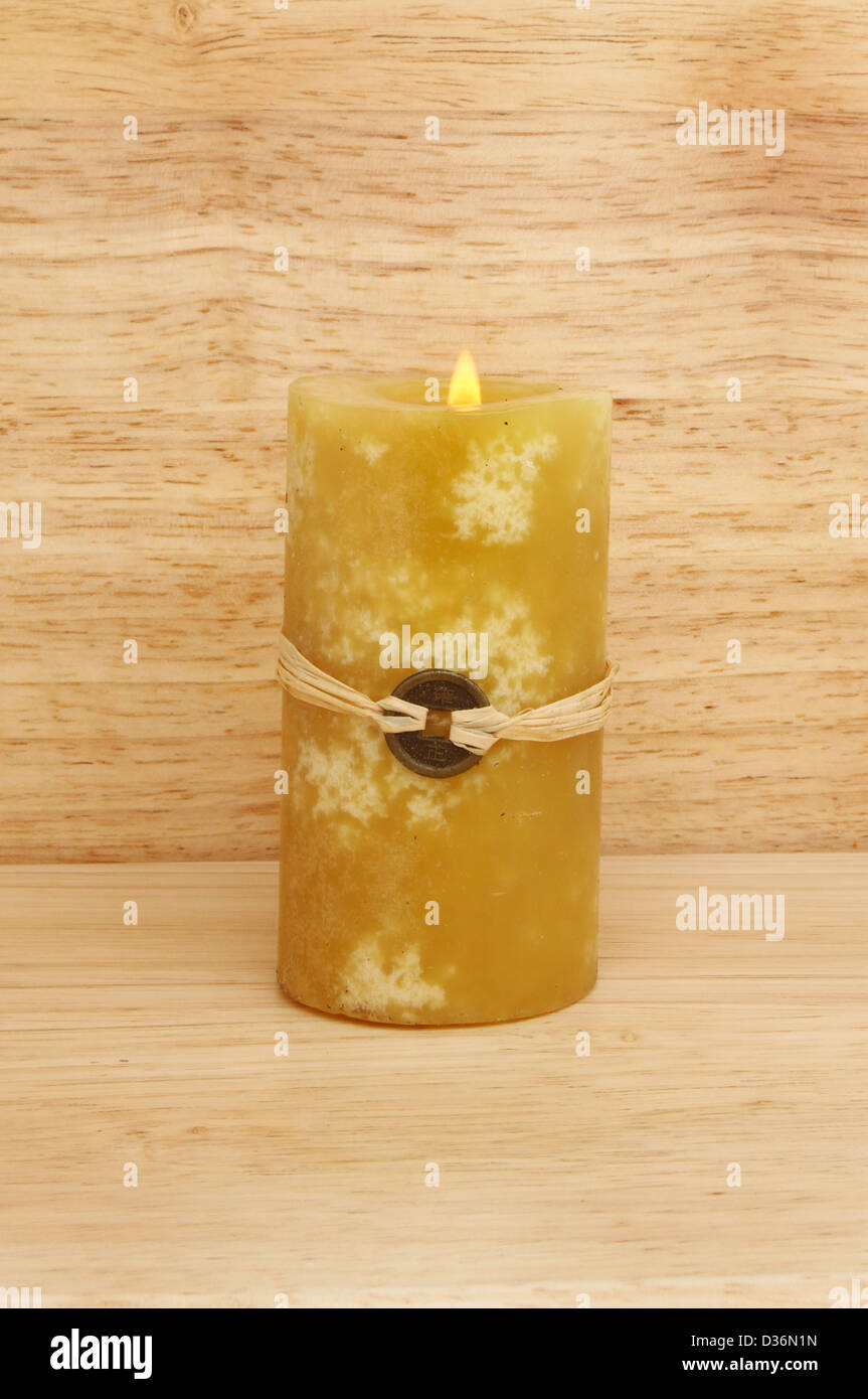La masterizzazione di giallo Feng Shui candela contro uno sfondo di legno Foto Stock