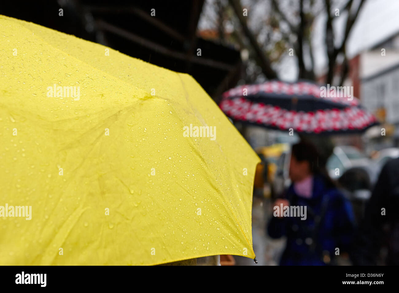 La pioggia cade fuori un ombrello giallo su fondo bagnato giorno piovoso nel centro cittadino di Vancouver BC Canada Foto Stock