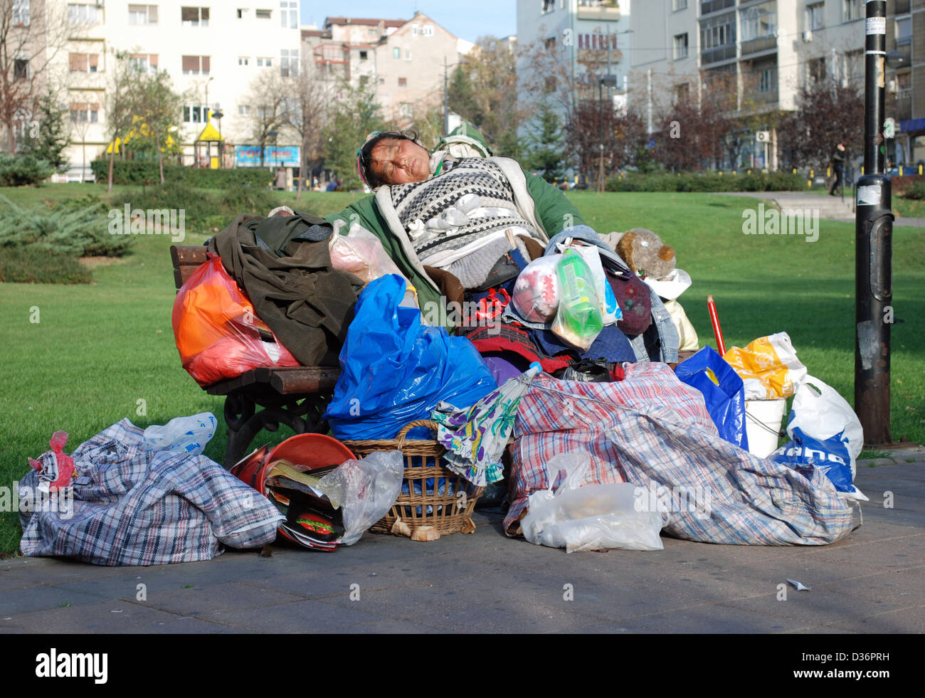 Un senzatetto gypsy donna con tutti i suoi averi di dormire su una panchina nel parco di Belgrado. Foto Stock