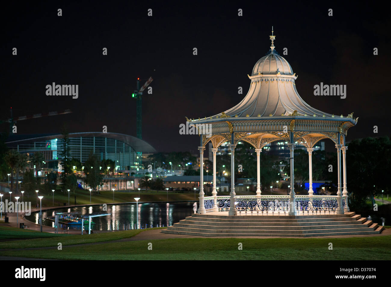 Gli ornati Elder Park Rotunda illuminata di notte fiancheggiata dal fiume Torrens e l'Adelaide Convention Centre Foto Stock