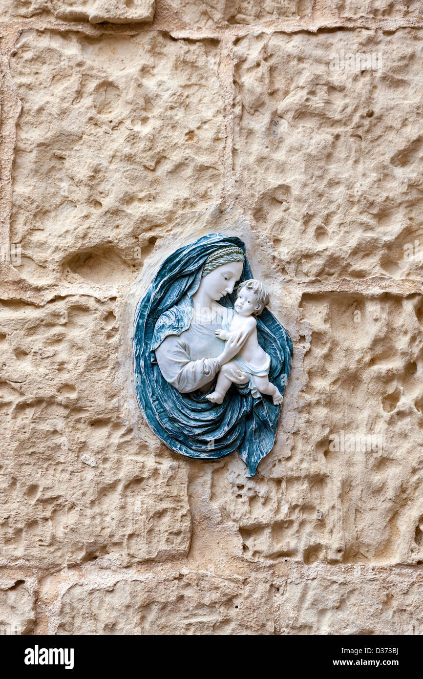 Un bel cast piastra a parete che raffigura la Vergine Maria e il Bambino Gesù, fissata ad una parete di pietra. Foto Stock