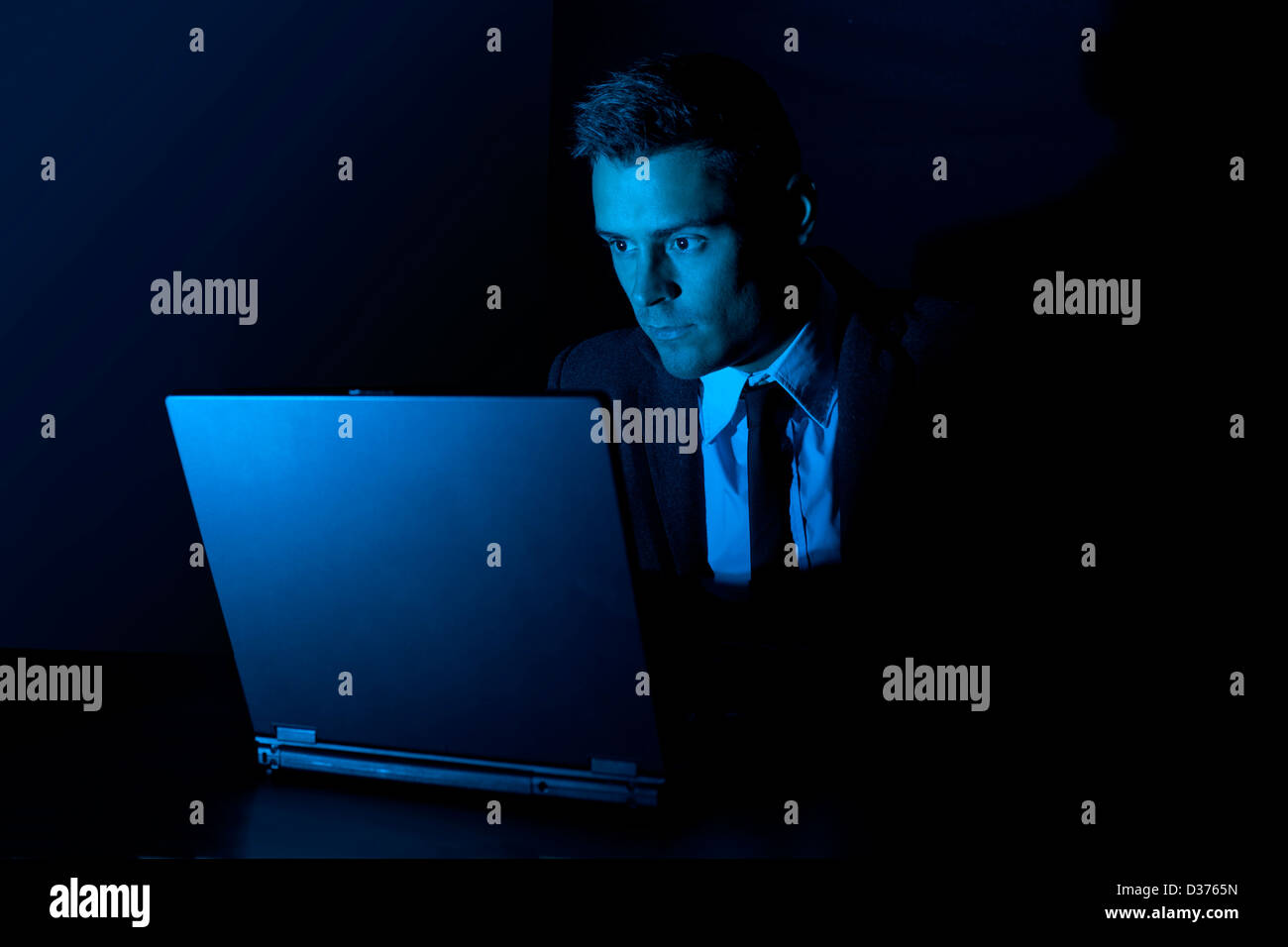 Uomo al lavoro su un computer portatile al buio Foto Stock