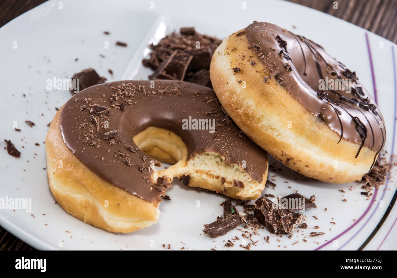 Ciambelle al cioccolato su una piastra su sfondo di legno Foto Stock