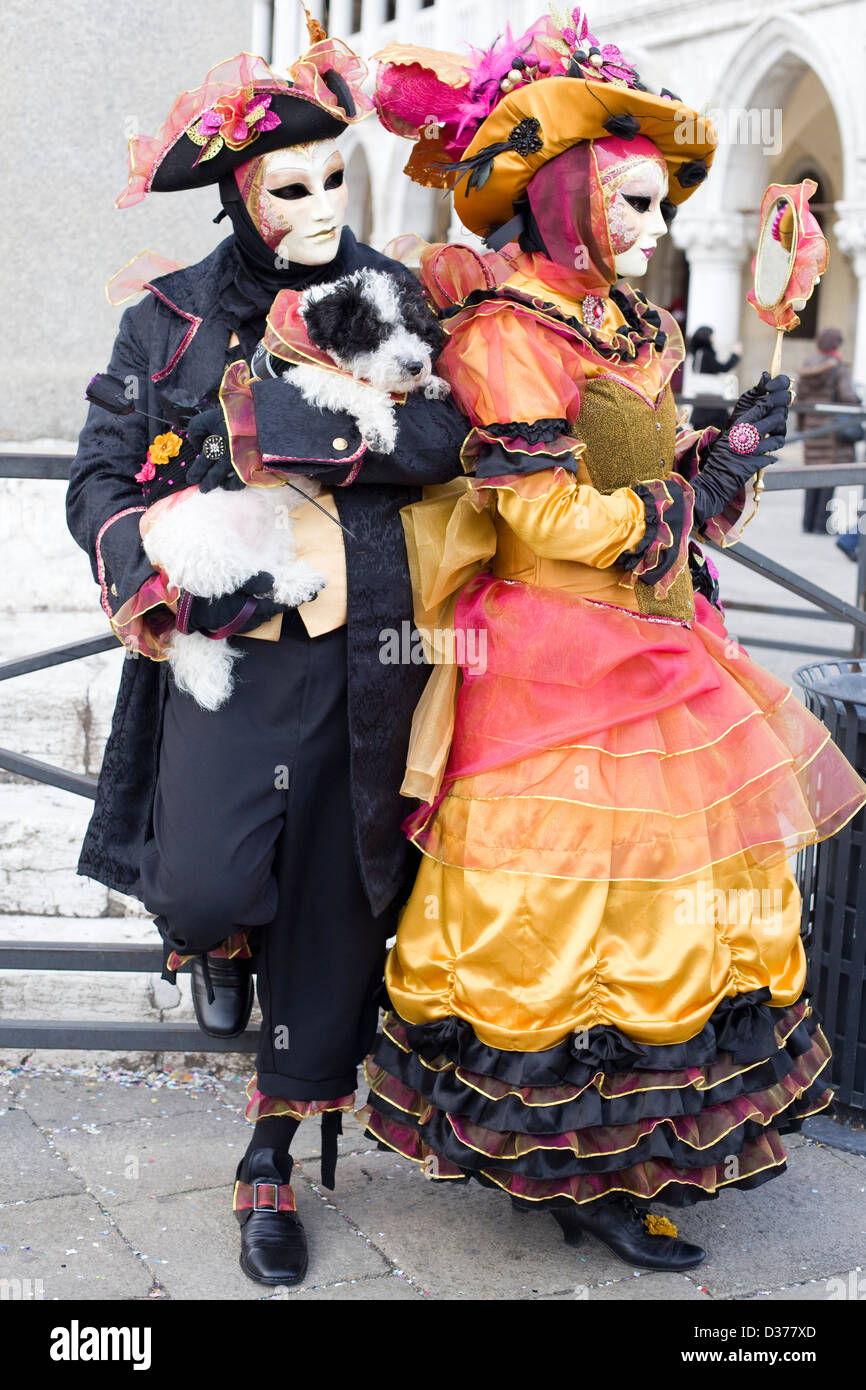 Gentleman e Lady tenendo un cane vestito in costume veneziano su di un ponte a Venezia Italia Foto Stock