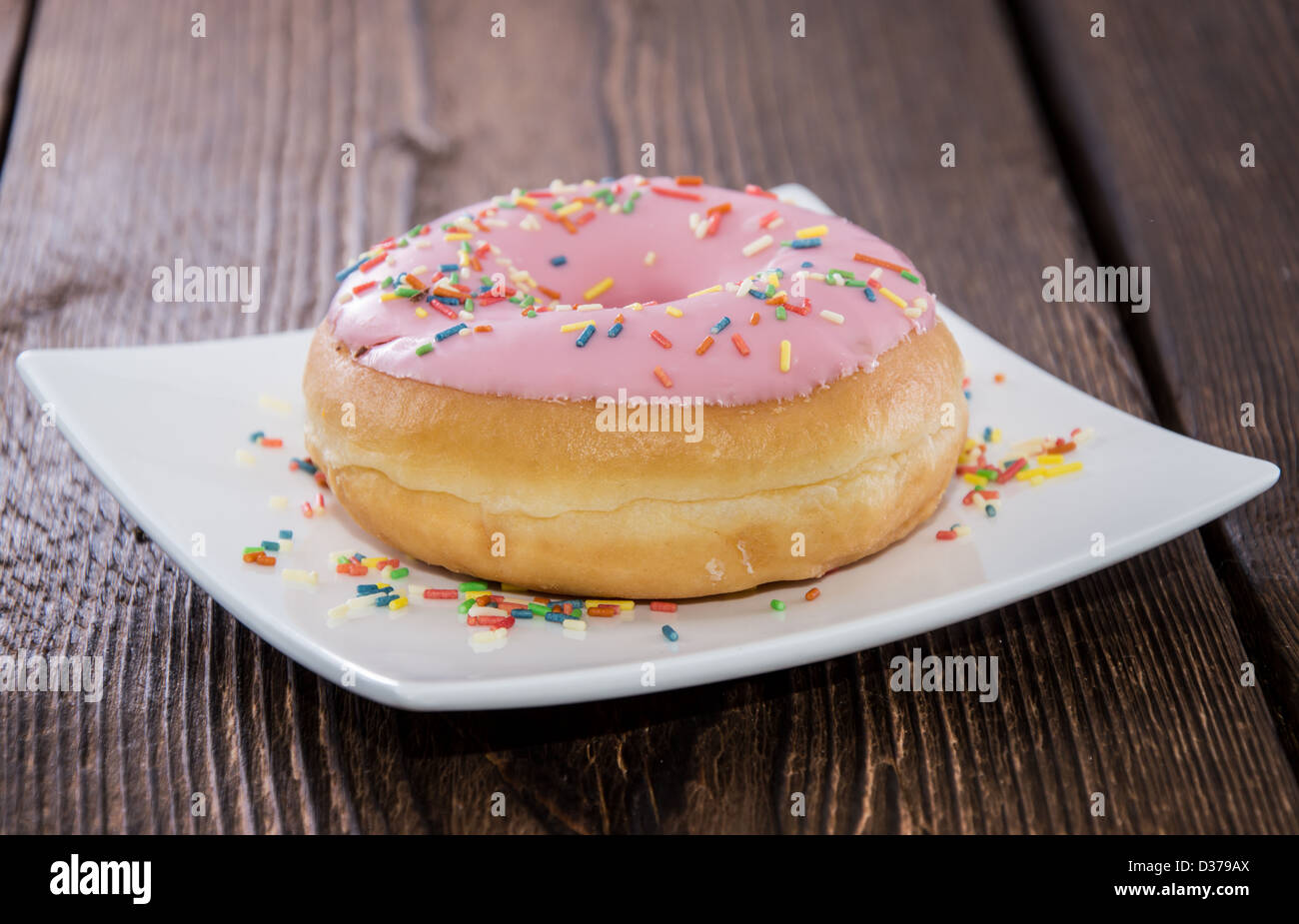 Unico ciambella rosa su una lastra di legno (fondo) Foto Stock