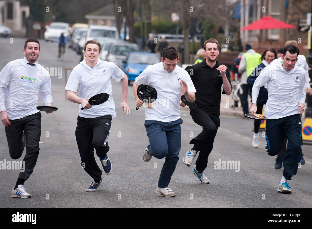 I concorrenti di sesso maschile (con padelle) prendendo parte, acceso o racing in tradizionale, Ilkley Rotary Pancake Race - The Grove, Ilkley, West Yorkshire, Regno Unito. Foto Stock