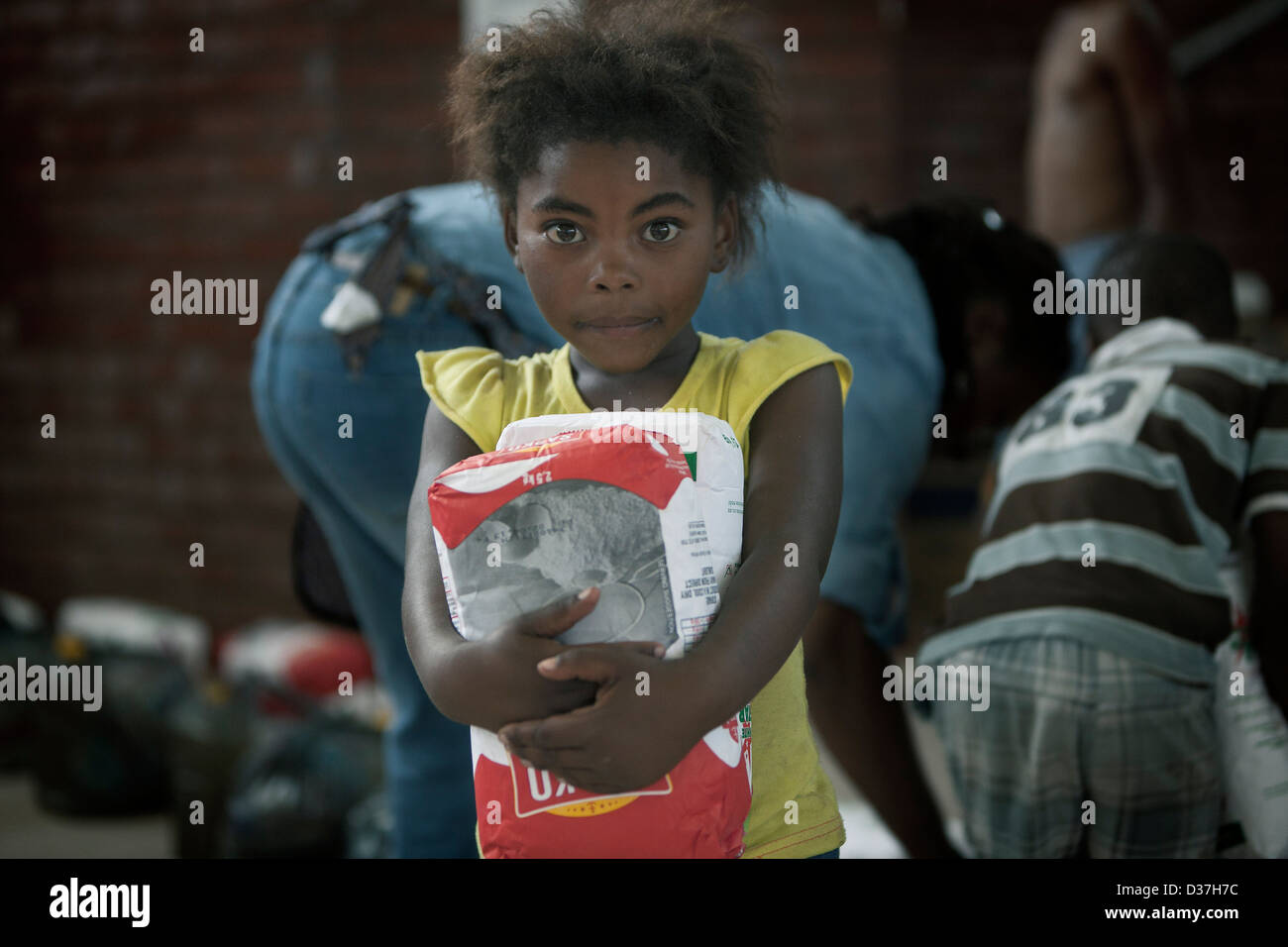 Un giovane e povero bambino africano trasporta alimenti confezionati. Foto Stock