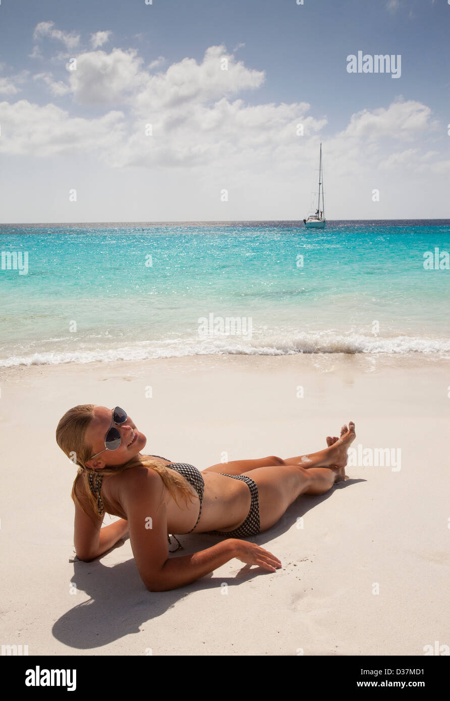Donna sorridente a prendere il sole sulla spiaggia Foto Stock