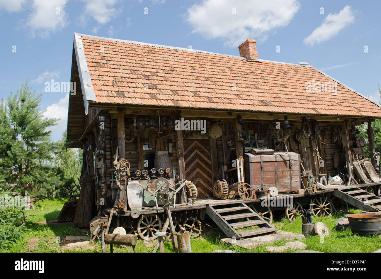 Varie retrò strumenti rurale vicino al old log in legno casa. Foto Stock