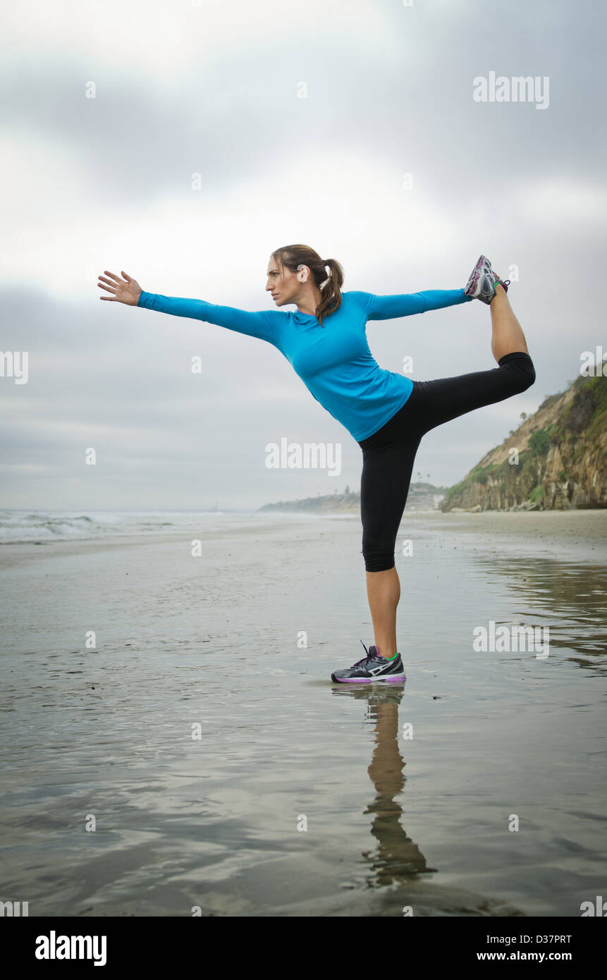 Runner a praticare yoga sulla spiaggia Foto Stock