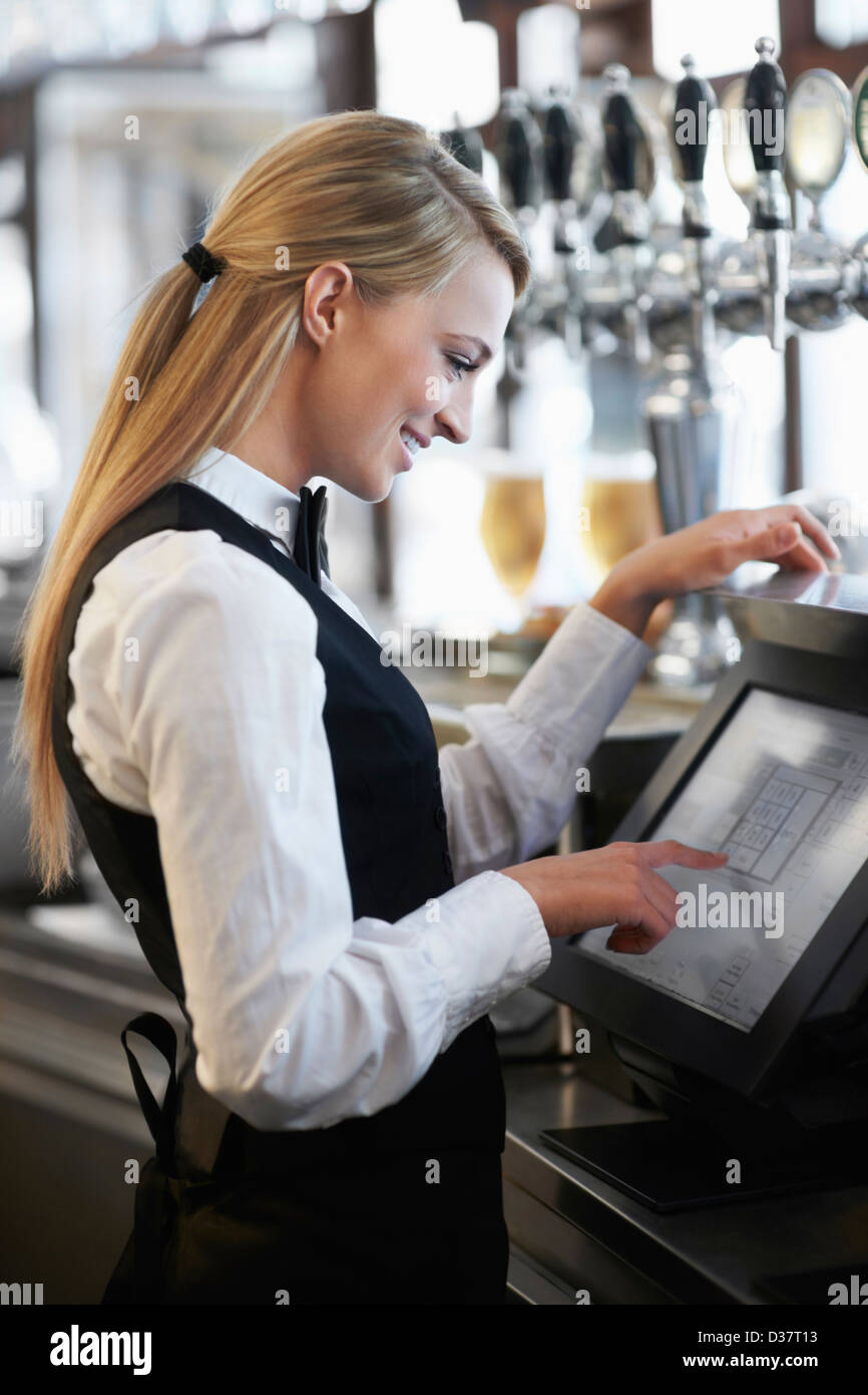 Danimarca, Aarhus, giovane cameriera utilizzando computer presso il ristorante counter Foto Stock