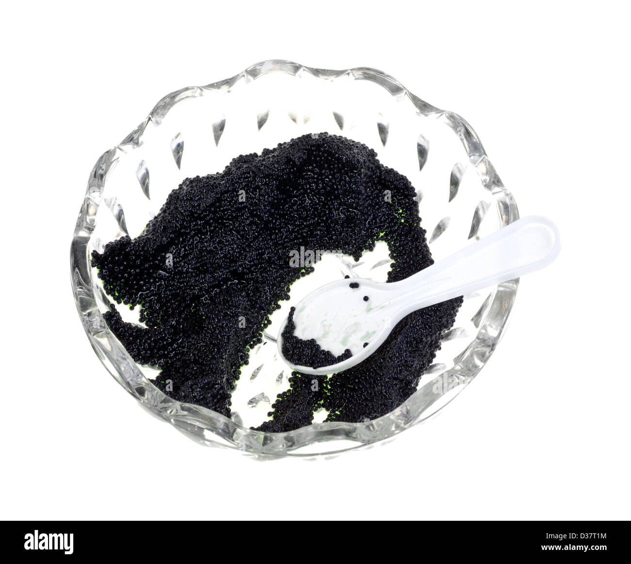 Una piccola ciotola di vetro con una piccola quantità di caviale nero e cucchiaino di colore bianco su uno sfondo bianco. Foto Stock