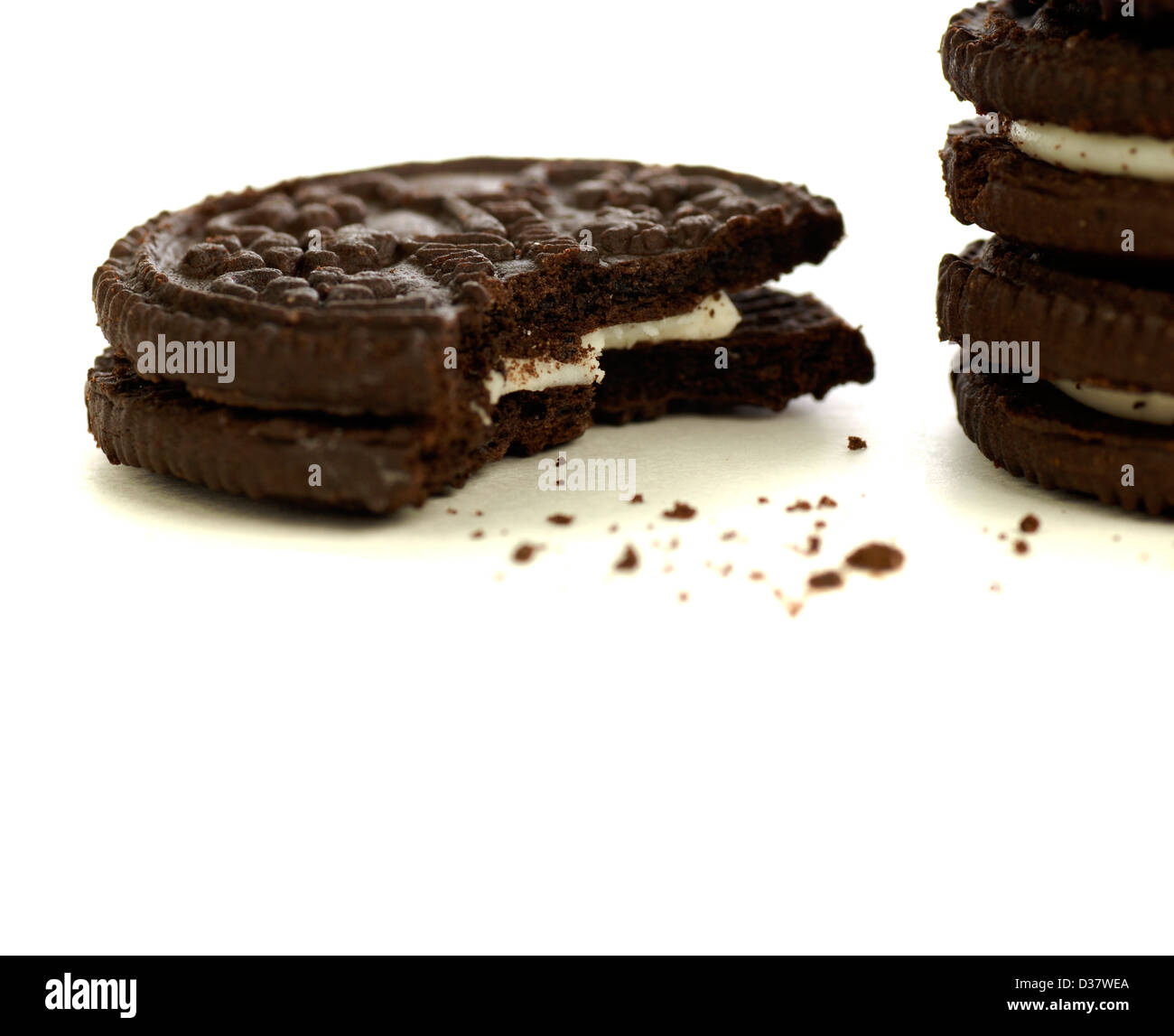 Biscotti al cioccolato con crema di riempimento e briciole su sfondo bianco Foto Stock