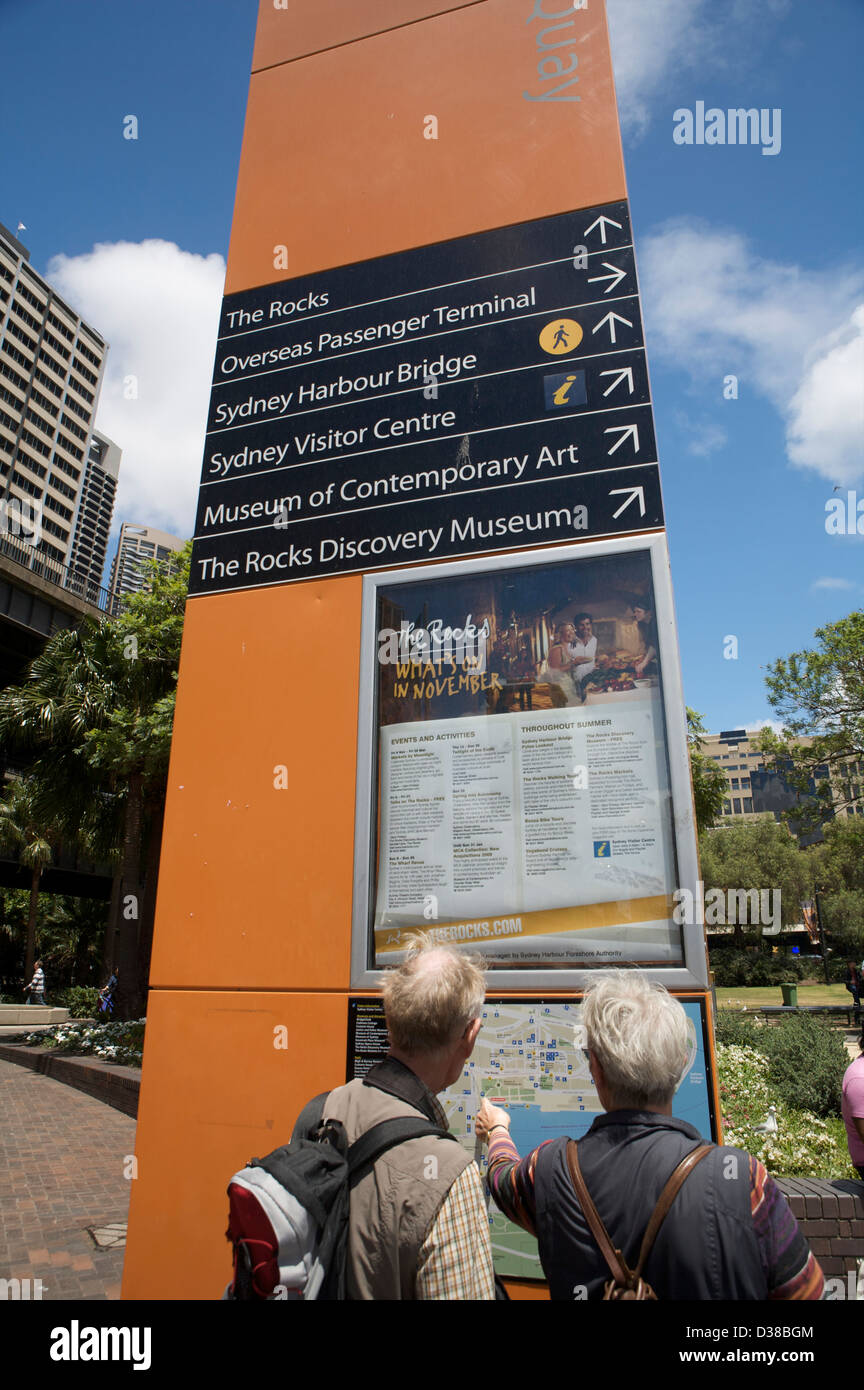 Un grande arancione punto informazioni segno a Circular Quay di Sydney Australia con indicatori a dire alla gente che la strada da percorrere. Foto Stock