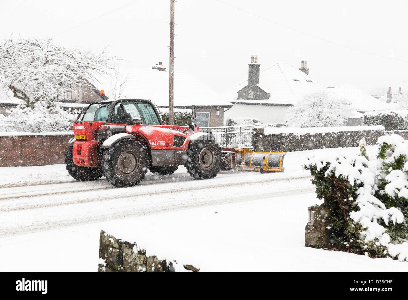 Johnshill, Lochwinnoch, Renfrewshire, Scozia, Regno Unito, mercoledì 13 febbraio 2013. Un movimentatore telescopico Manitou spazzaneve sgombrare la neve dalla strada principale attraverso il villaggio. Foto Stock