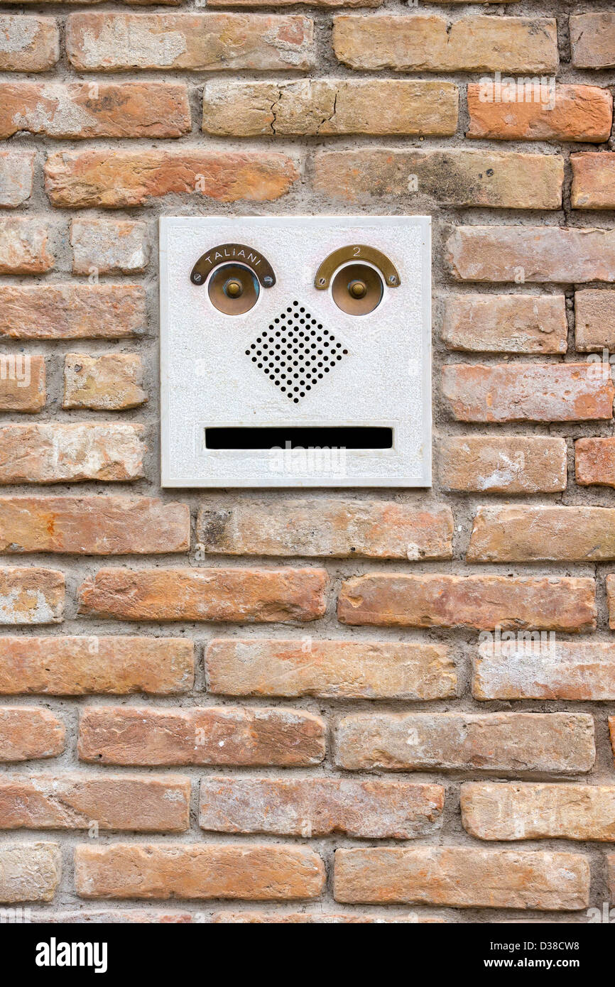 Letterbox antropomorfo e campanelli) impostato in un muro di mattoni e che assomiglia alla testa di un robot. Foto Stock