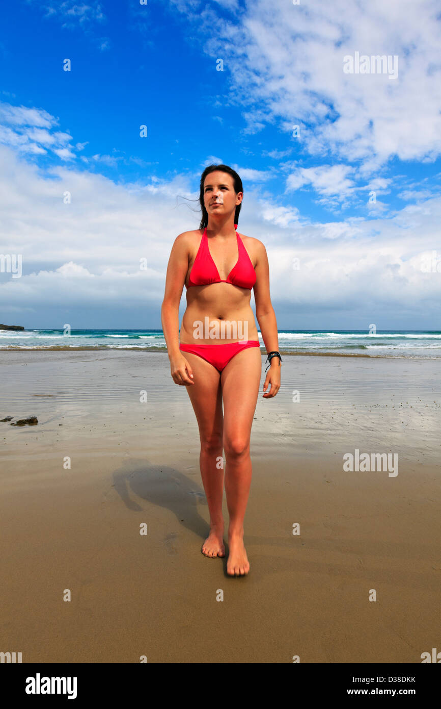 Una giovane donna su una spiaggia remota nel tardo pomeriggio Foto Stock