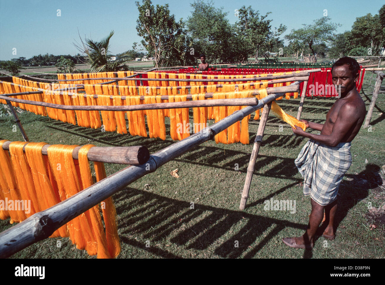 Operai che asciugano fibre di iuta tinte su pali orizzontali, per decorare biciclette, rickshaws e camion motorizzati. Narayanganj, Bangladesh Foto Stock