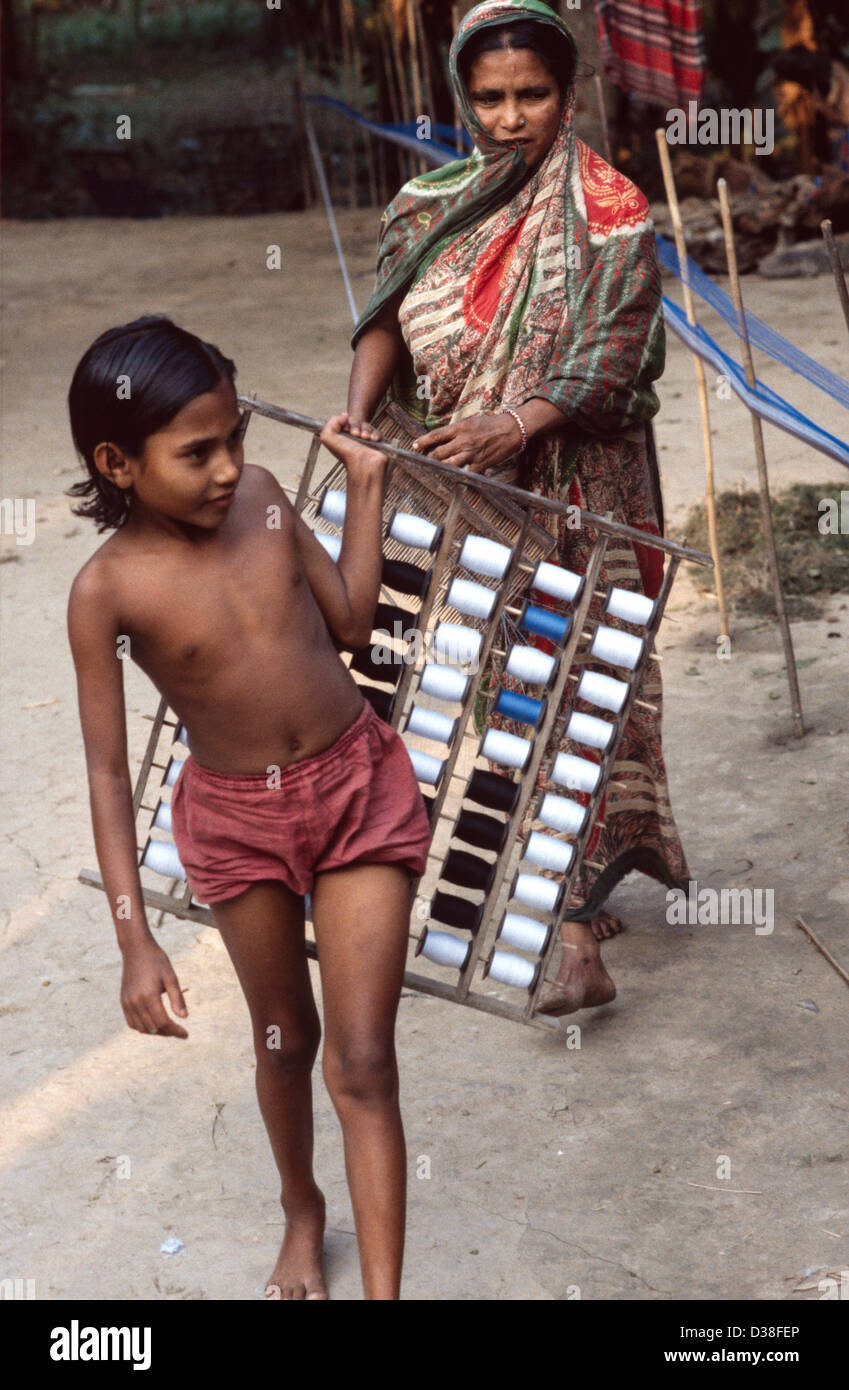 Ragazza aiutando la madre di stringa di cotone colorato prima della tessitura. Rajoir, Bangladesh Foto Stock