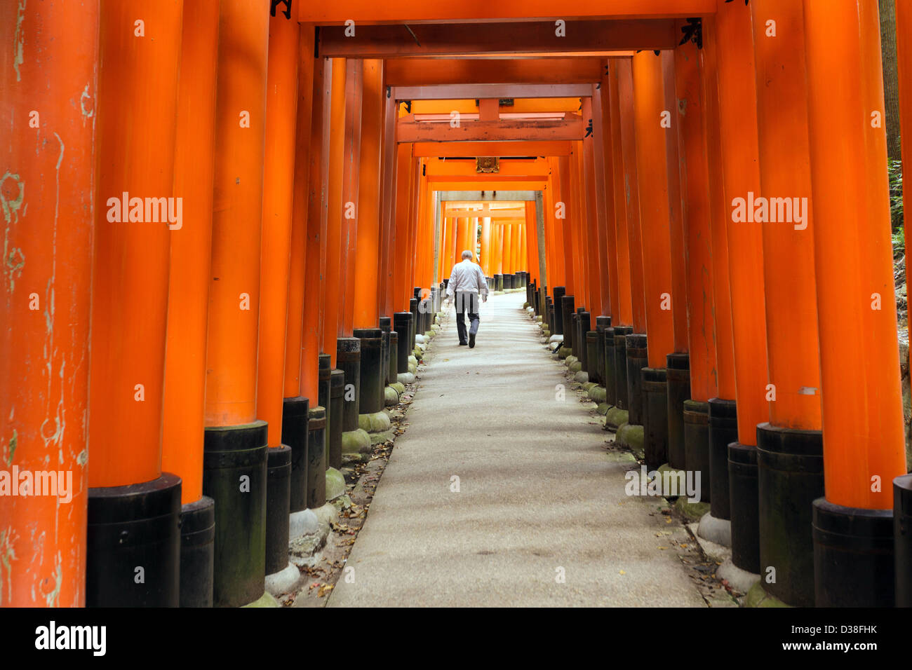 Uomo giapponese a piedi in Fushimi Inari santuario torii in tunnel di Kyoto, Giappone Foto Stock