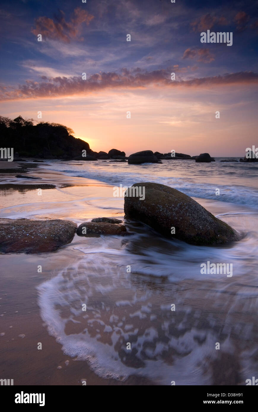 Il lavaggio delle onde sulle rocce sulla spiaggia Foto Stock