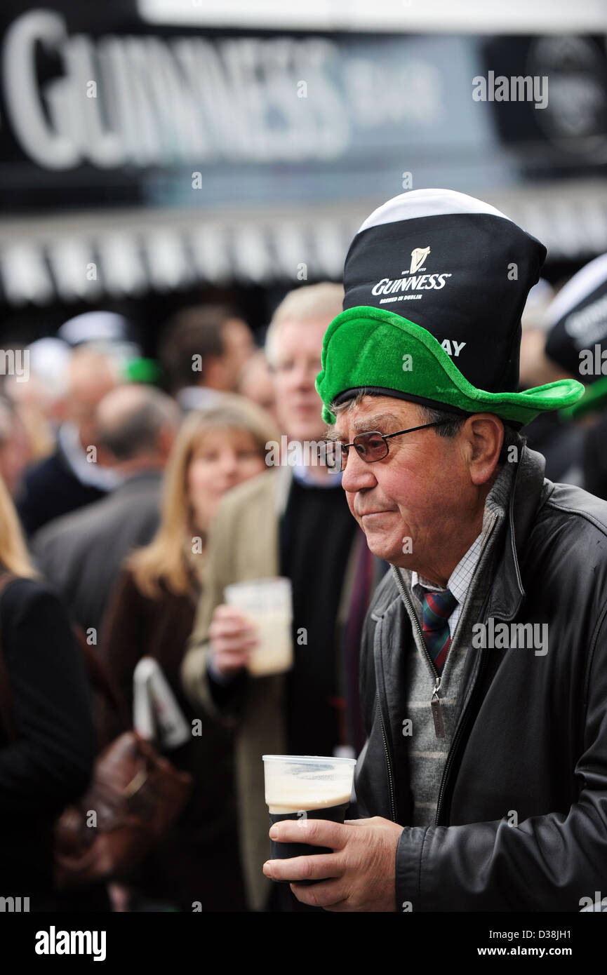 Un uomo beve una pinta di Guinness di San Patrizio giorno durante il Cheltenham horse racing festival Foto Stock