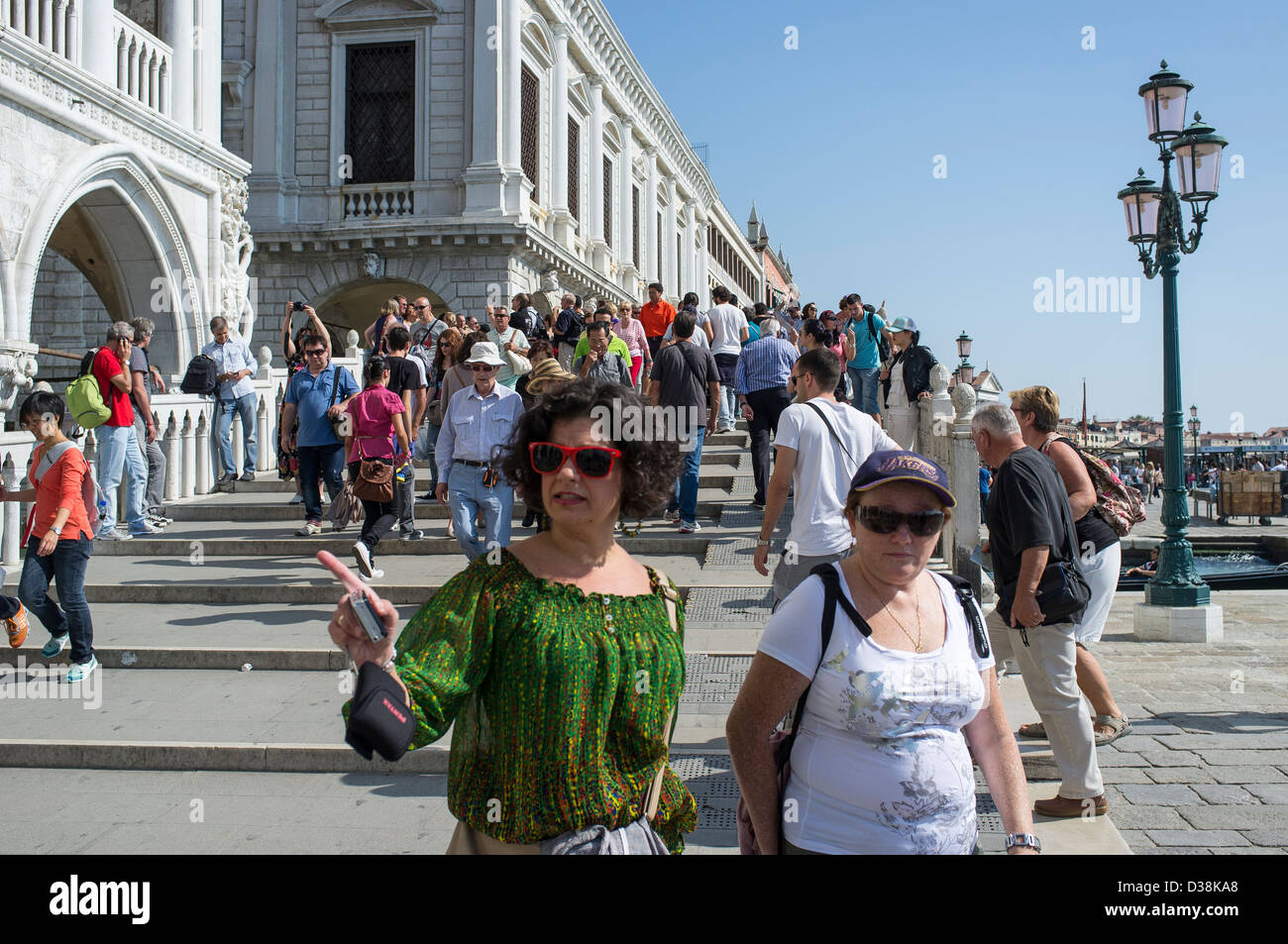 La folla di turisti attraversando un ponte sulla Riva degli Schiavoni, di fronte al Palazzo Ducale Venezia Foto Stock