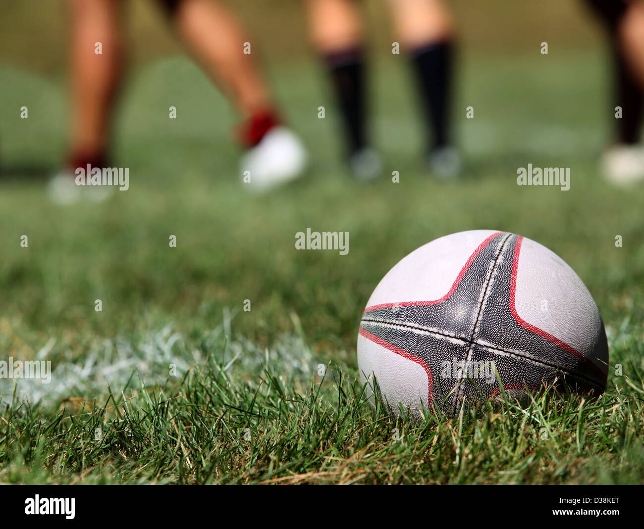 Pallone da rugby su un'erba su uno sfondo di gambe di giocatori Foto Stock